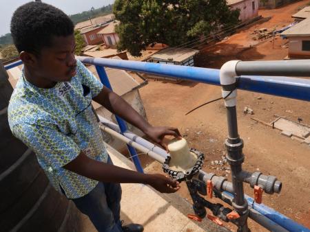 Martin Agyepong Safe Water Network field services officer checks a filter on the water tower at Wamahinso