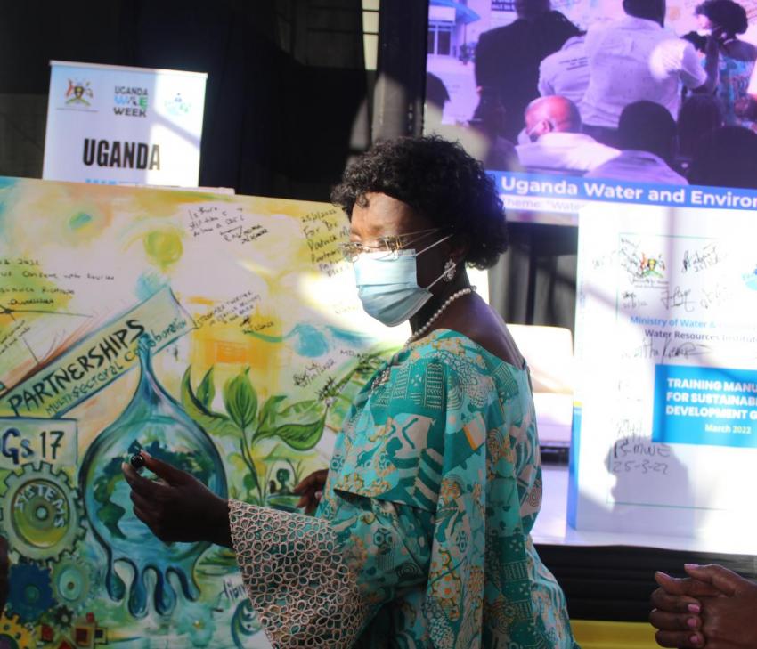 First Deputy Premier Rt Hon Rebecca Kadaga signs the mural created in real time during the closing ceremony