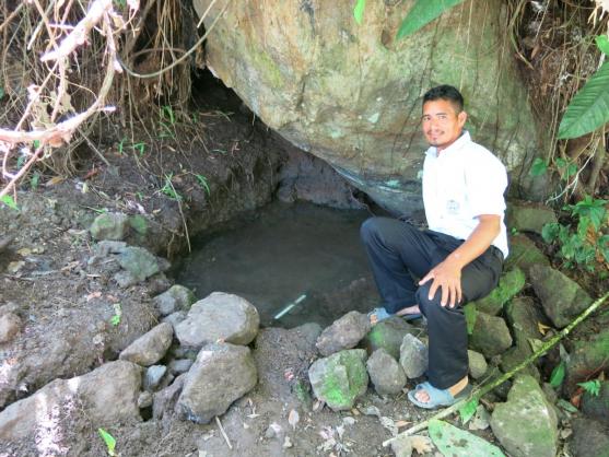 Mr. Enoc showing the spring and the tube that carries the water to his house