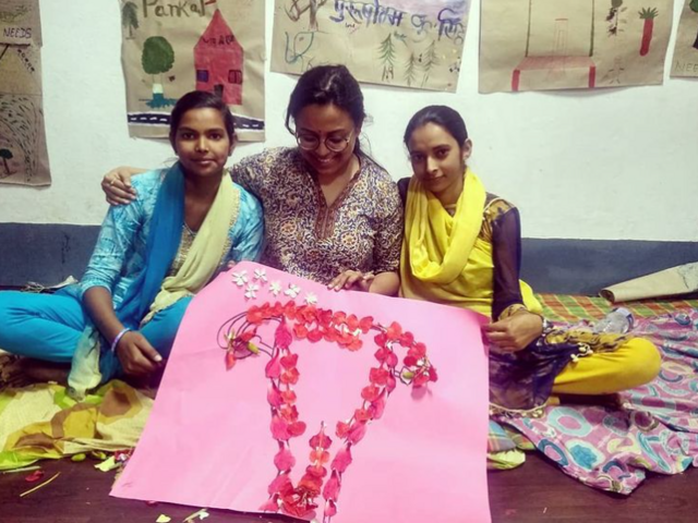 Two girls Zeba and Anjum show poster of uterus made out of Gulmohor flower for Menstrual Hygiene Day.