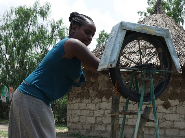 Woman getting water with rope pump 