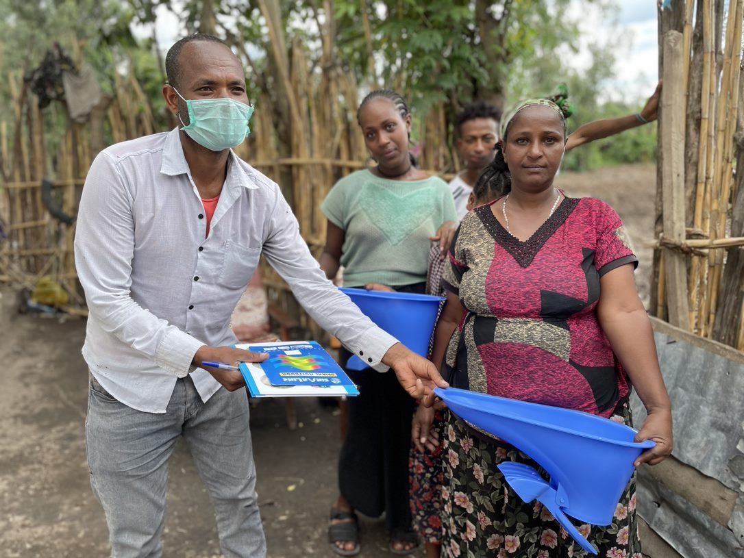 Ethiopia. Salesman handing plastic latrine slab to female customer