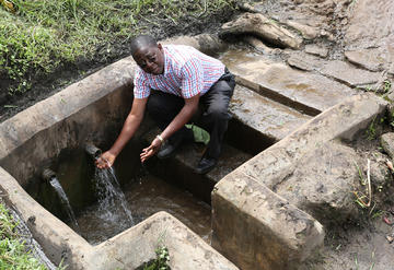Eng. Aaron Kabirizi, Commissioner for Rural Water Supply and Sanitation, checks the water from a protected spring in Rwebijooka, Buheesi in Kabarole district.